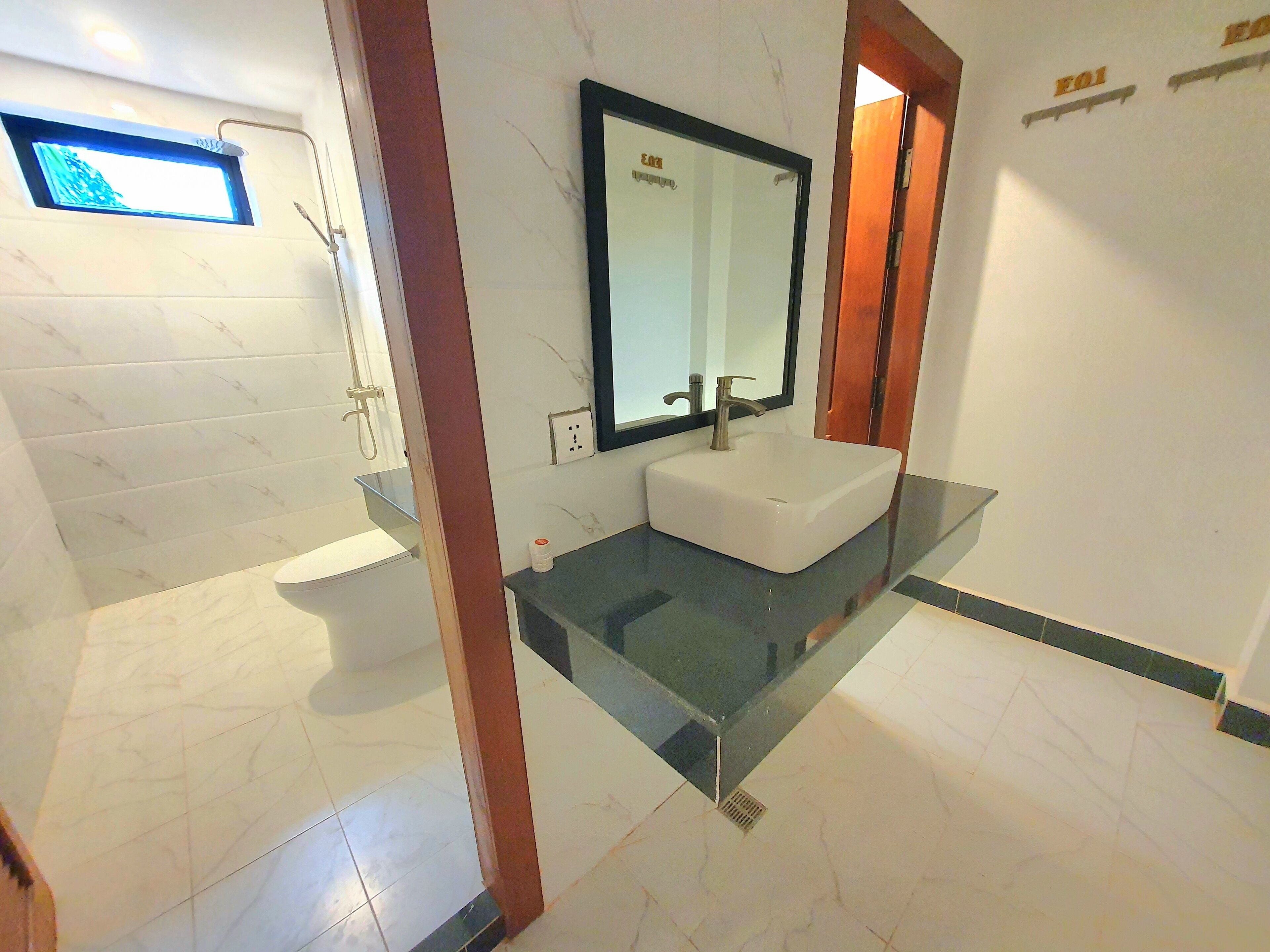A modern bathroom with a glass-enclosed sink, a built-in shower, and a large mirror.