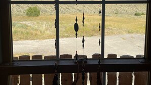 A rustic interior with a large window overlooking a desert landscape.