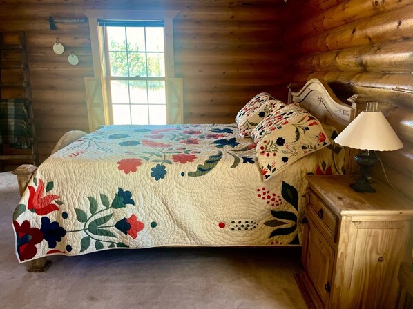 A wooden cabin bedroom with a bed, a nightstand, and a window.