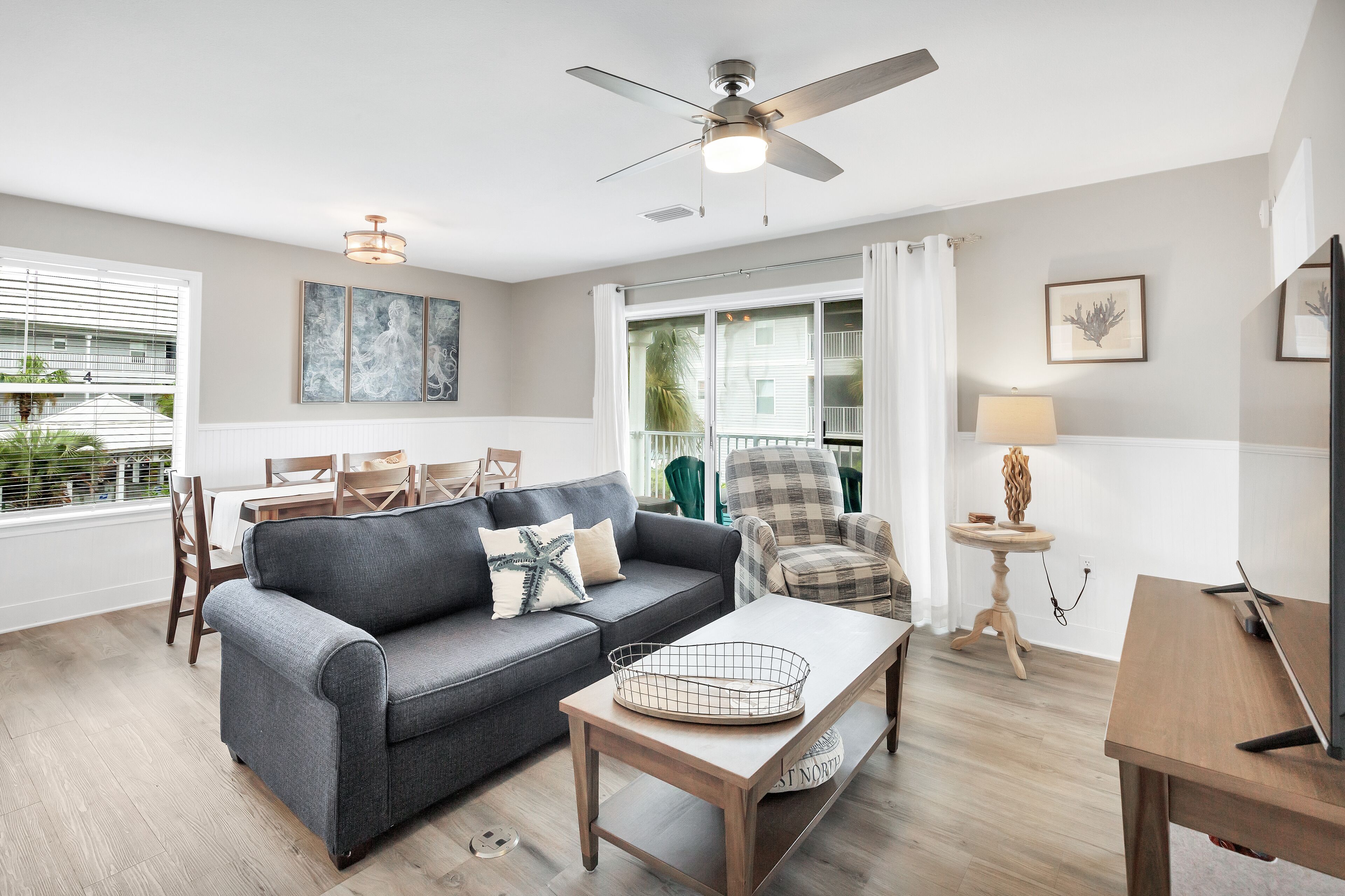 Ein Wohnzimmer mit grauem Sofa, Couchtisch aus Holz und Deckenventilator.