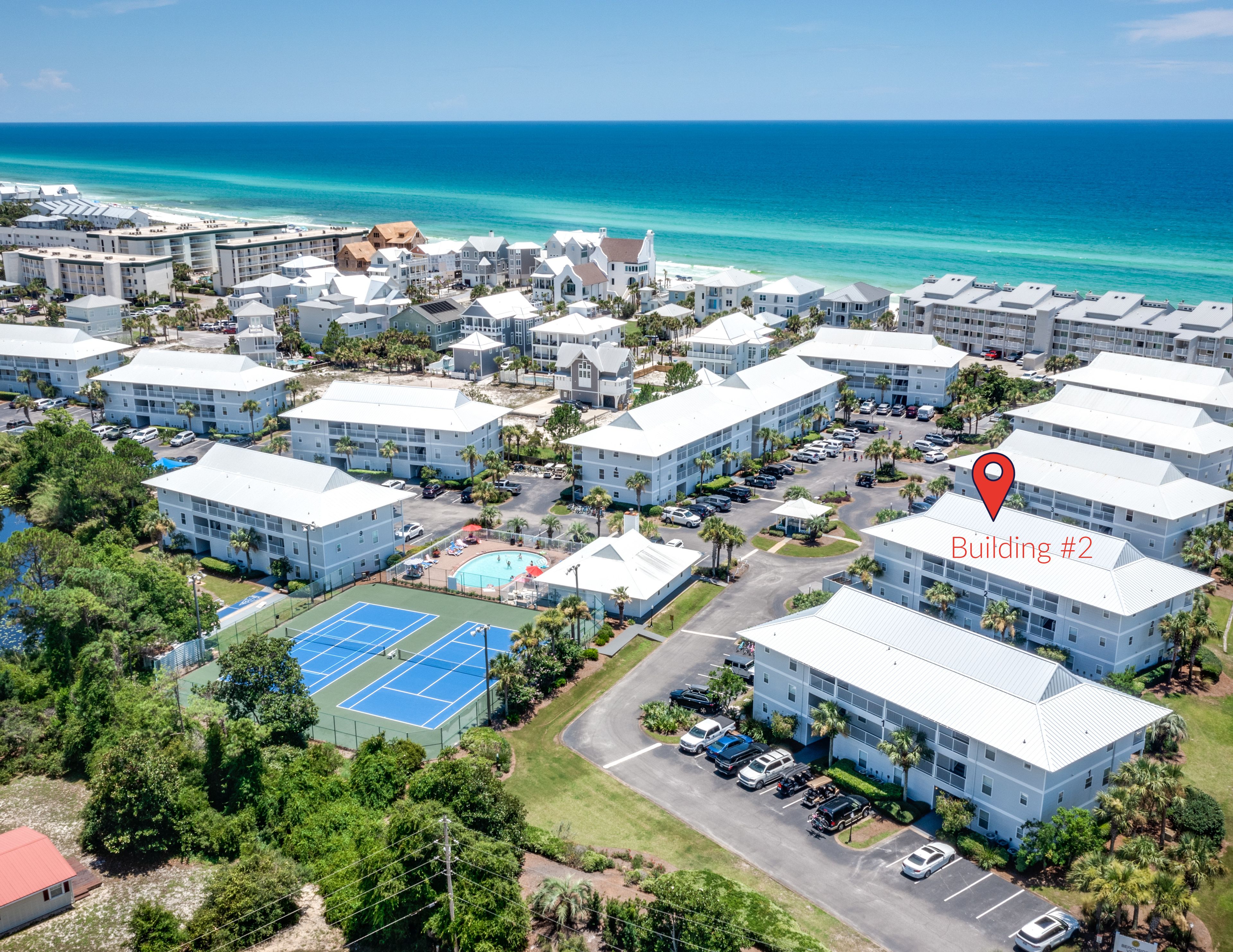 A resort with multiple buildings, a tennis court, and beach access.