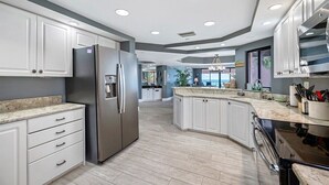 Una cocina moderna con armarios blancos, electrodomésticos de acero inoxidable y encimera de mármol.