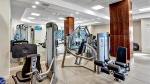 Een sportschool met diverse fitnessapparaten, een spiegel en een houten pilaar.
