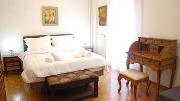 A bedroom with a large bed, a wooden bench, a nightstand, and a dresser.