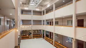 A multi-level hotel interior with balconies, string lights, and a central open space.