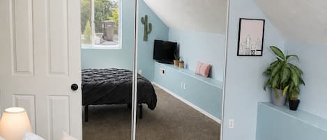 A bedroom with a bed, a ceiling fan, a TV, and a sliding door leading to a balcony.