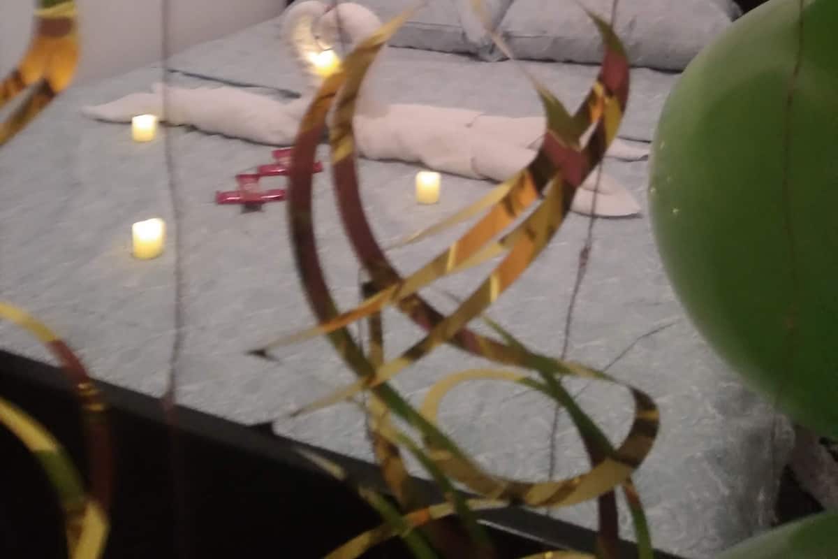 A bedroom with a bed, pillows, and a wall with a 'Happy Birthday' sign.