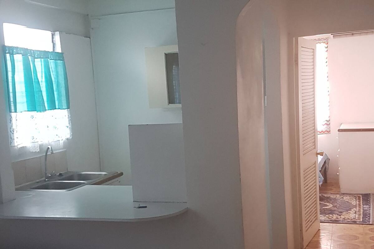 A room with a bed, a small kitchenette, and a bathroom.