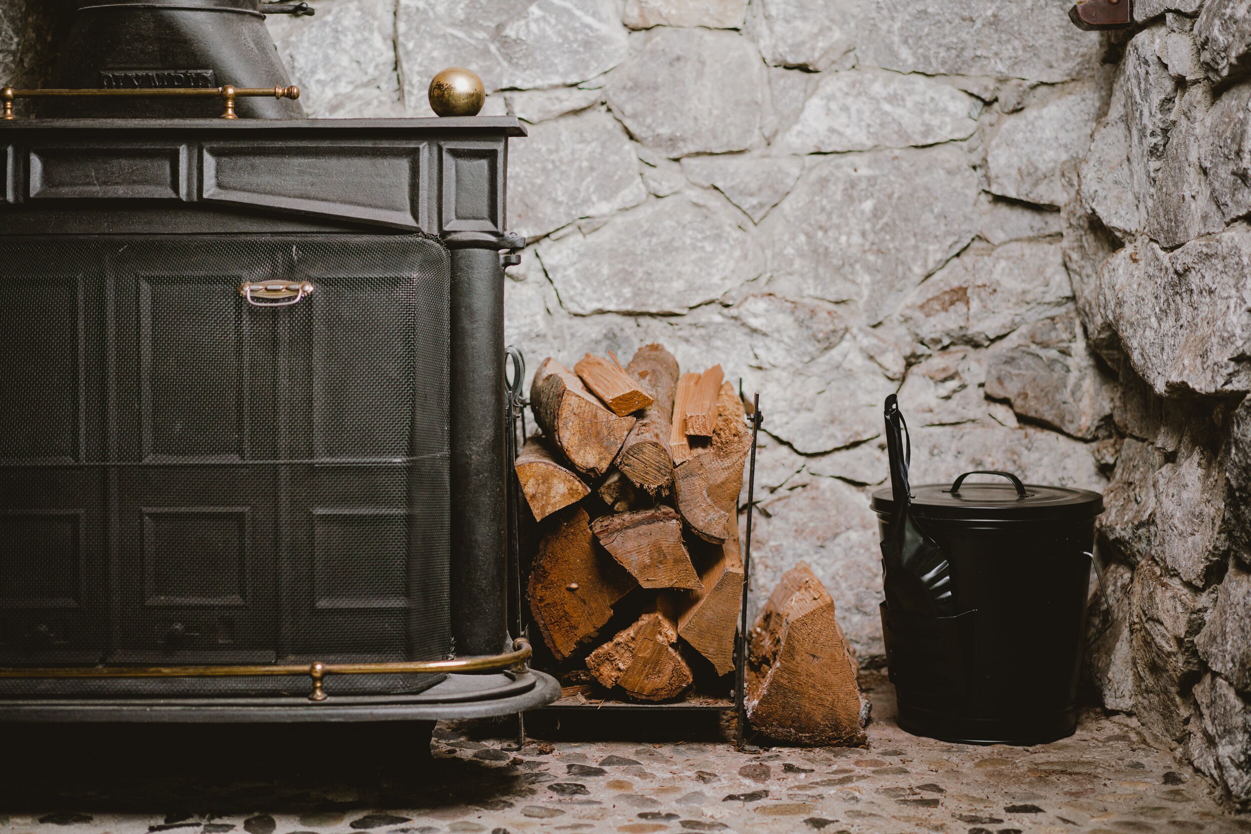A traditional wood-burning stove with a metal pot on a stone wall.