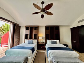 A hotel room with two beds, a ceiling fan, a nightstand with a lamp, and a view of the outdoors.