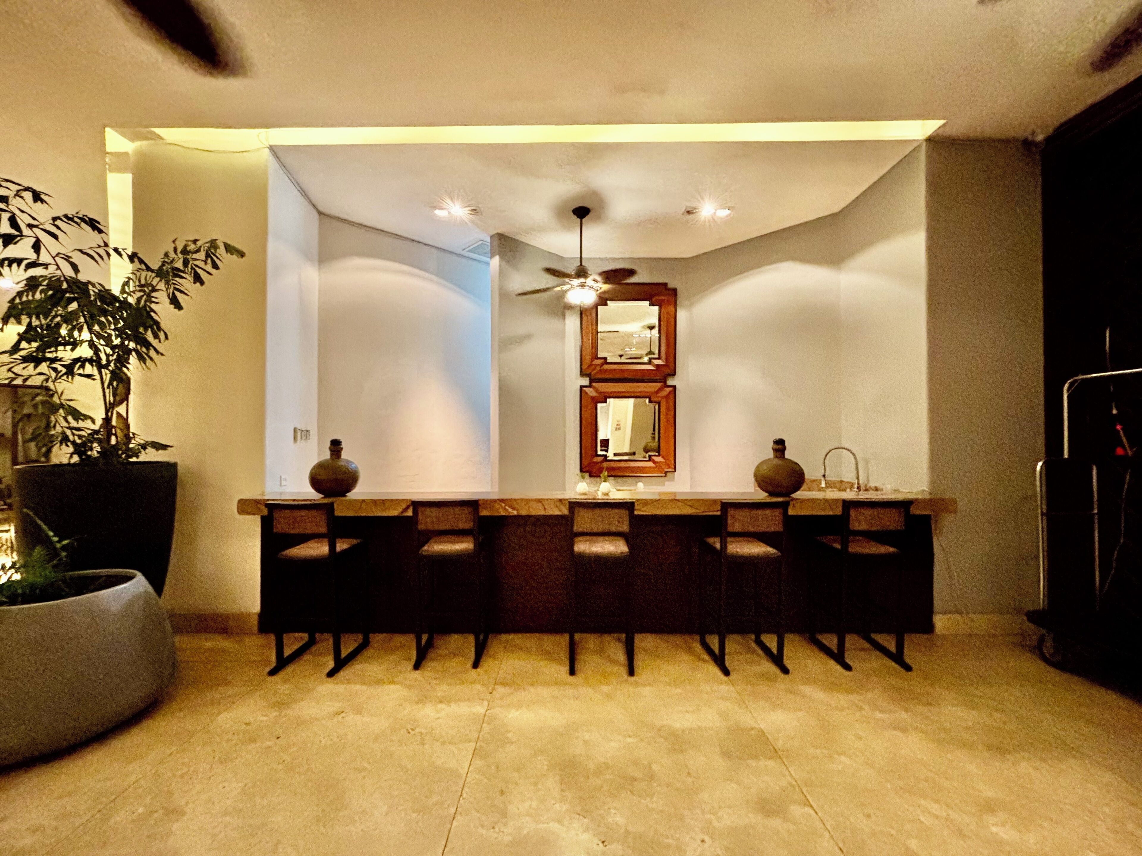 A modern kitchen with a central island, a ceiling fan, and a potted plant.