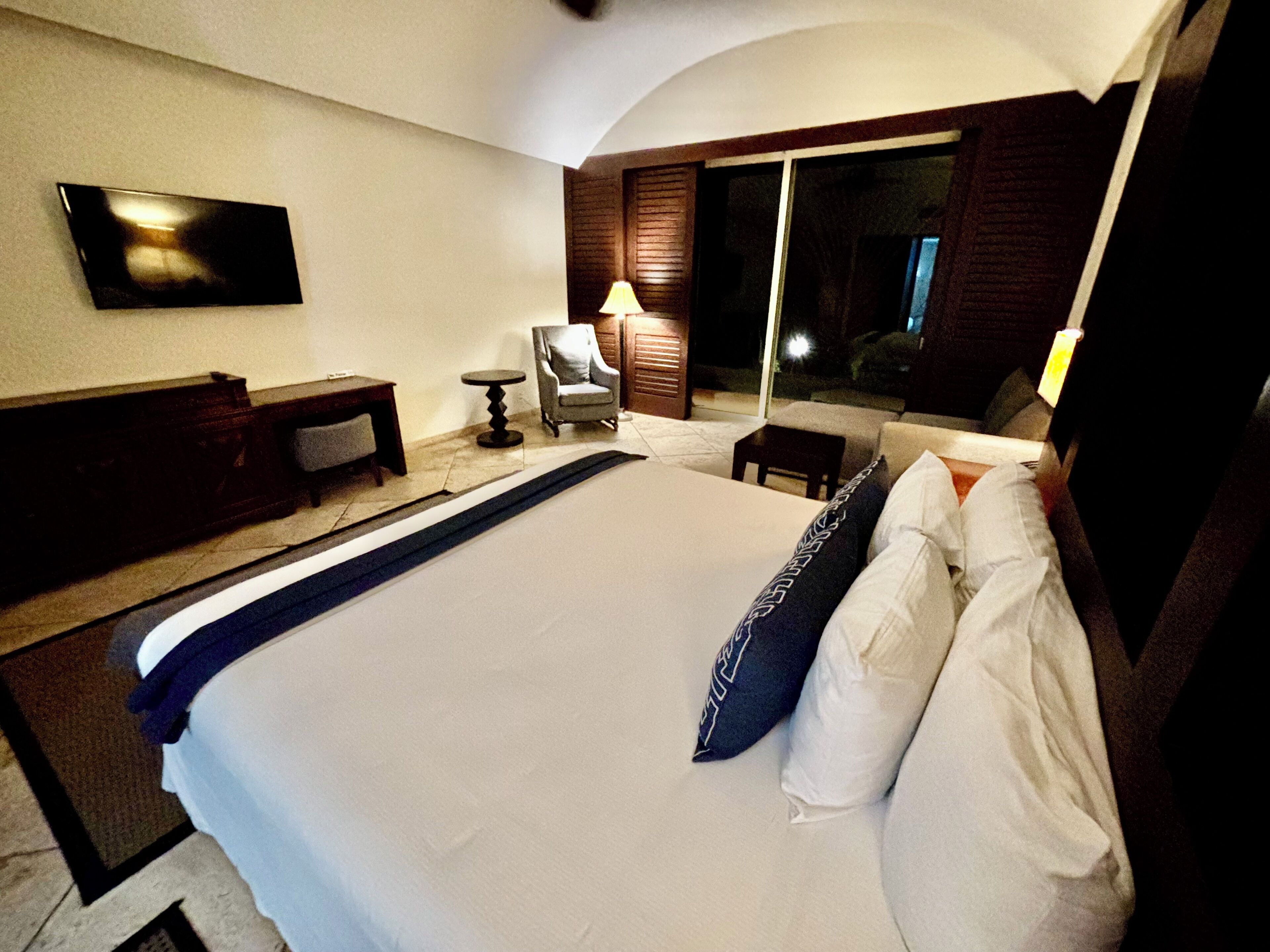 Een hotelkamer met een groot bed, een bureau, een stoel en een televisie aan de muur.