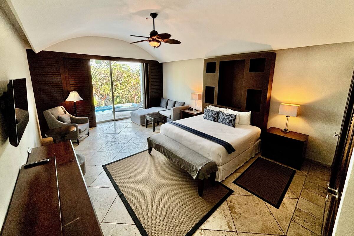 Une chambre d’hôtel moderne, dotée d’un grand lit, d’un canapé, d’un bureau et d’une télévision.