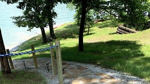 Un sendero de piedra conduce a una terraza de madera con vistas a un lago.