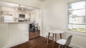 A kitchen with white cabinets, a microwave, and a dining area with a round table and chairs.