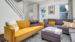 A living room with a yellow sofa, a grey sofa, and a patterned rug.