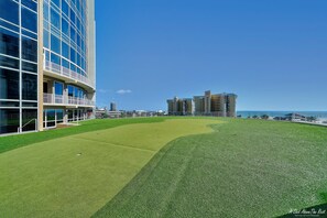 A modern building with a glass facade and a grassy area in front.