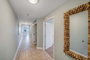 A hallway with a tiled floor, white doors, and a large mirror with a wooden frame.