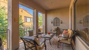 A balcony with a seating area, including chairs and a table, and a view of a building in the background. - Serenity Town House! Heated Pool, Gym! 2 King Beds! 1 Dog Friendly! (Chandler)