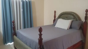 Una cama con cabecera de madera y colcha gris.