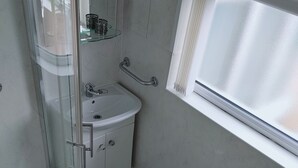 Une salle de bain avec une douche à parois de verre, un lavabo blanc et des toilettes.