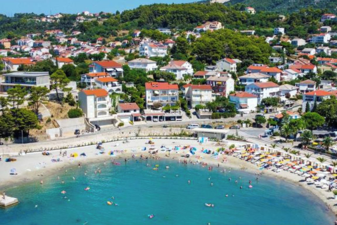 A coastal town with a beach, houses, and a clear sky.