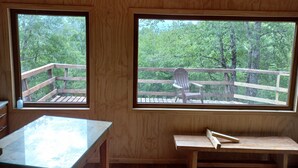 A cabin with two large windows offering views of a wooden deck and surrounding forest. - Parque Nacional Conguillio, frente al Volcán, la mejor vista (Melipeuco)
