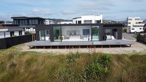 Una casa moderna con una amplia terraza, una cocina con comedor y vistas del barrio circundante.