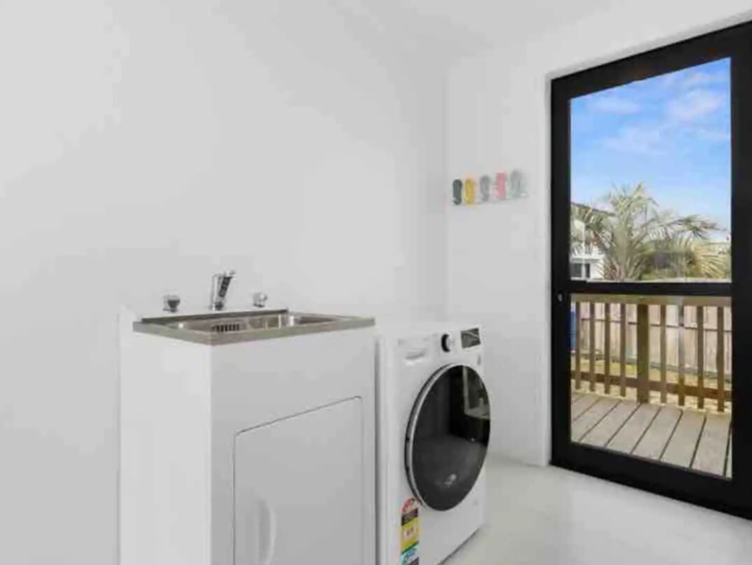 A laundry room with a washing machine and a sink.