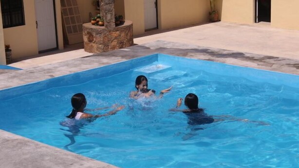 A rectangular swimming pool with three people in the water. - Hotel La Piramide Izamal (Izamal)