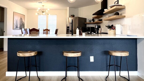 A modern kitchen with a central island, bar stools, pendant lighting, and a view of the adjacent living area. - Scenic views on a quiet fishing cove. Boat Slip, Kayaks, Peddle Boat, SUPs. (Sunrise Beach Village)