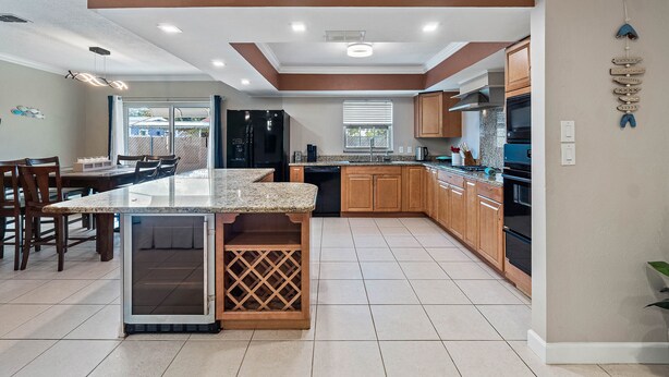 A modern kitchen with a central island, wooden cabinets, and a dining area with chairs. - Near Tesla's Building - Centralized location (St. Petersburg)