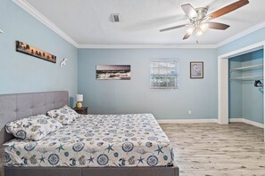 Une chambre à coucher avec un lit, un ventilateur de plafond et une fenêtre avec des stores.