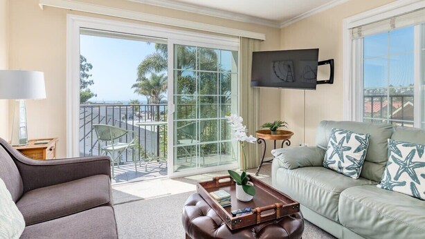 Un salon comprenant un canapé, une table basse, un téléviseur fixé au mur et un balcon avec vue.