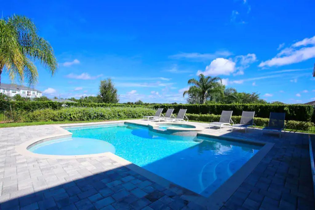 A swimming pool with lounge chairs and a paved deck.