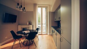 Eine moderne Küche mit Essbereich, einem an der Wand montierten Fernseher und einer Glasschiebetür, die auf einen Außenbalkon führt.