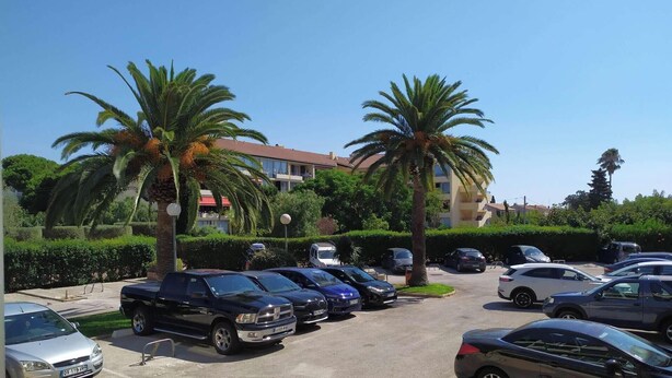 A parking lot with several cars, palm trees, and a building with balconies in the background. - 1 bedroom apartment close to the beach of Les Sablettes (LA SEYNE SUR MER)