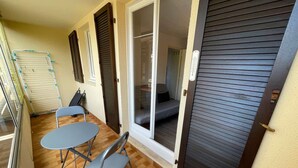A small balcony with a table and chairs, a sliding door, and a drying rack. - 1 bedroom apartment close to the beach of Les Sablettes (LA SEYNE SUR MER)