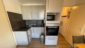 A compact kitchen with white cabinets, a microwave, an oven, a sink, and a trash bin. - 1 bedroom apartment close to the beach of Les Sablettes (LA SEYNE SUR MER)