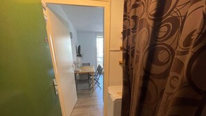 A narrow hallway with a wooden floor, a white door on the left, and a patterned curtain on the right. - 1 bedroom apartment close to the beach of Les Sablettes (LA SEYNE SUR MER)