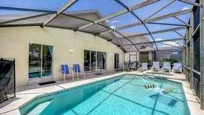 Une piscine intérieure à l’eau d’un bleu cristallin, entourée de chaises longues et d’un patio couvert.
