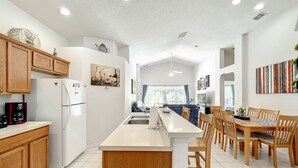 Une cuisine moderne avec des meubles en bois, un réfrigérateur blanc et un coin repas comprenant des chaises et une table en bois.