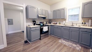 A modern kitchen with grey cabinets, a stainless steel oven, and a window providing natural light.