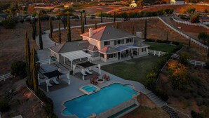 Une grande maison avec une piscine, un patio couvert et une cour clôturée.