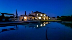 Une grande maison avec une piscine, au crépuscule.