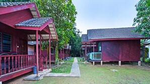 A row of red wooden cabins with a covered porch and a pathway leading through the property.