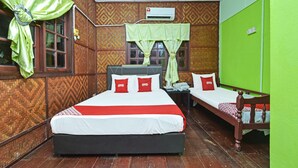 A room with two beds, a wooden floor, a green wall, and a patterned wall.