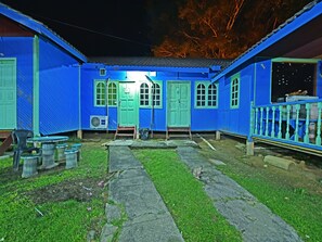 Una casa azul con un porche, una mesita y una silla.