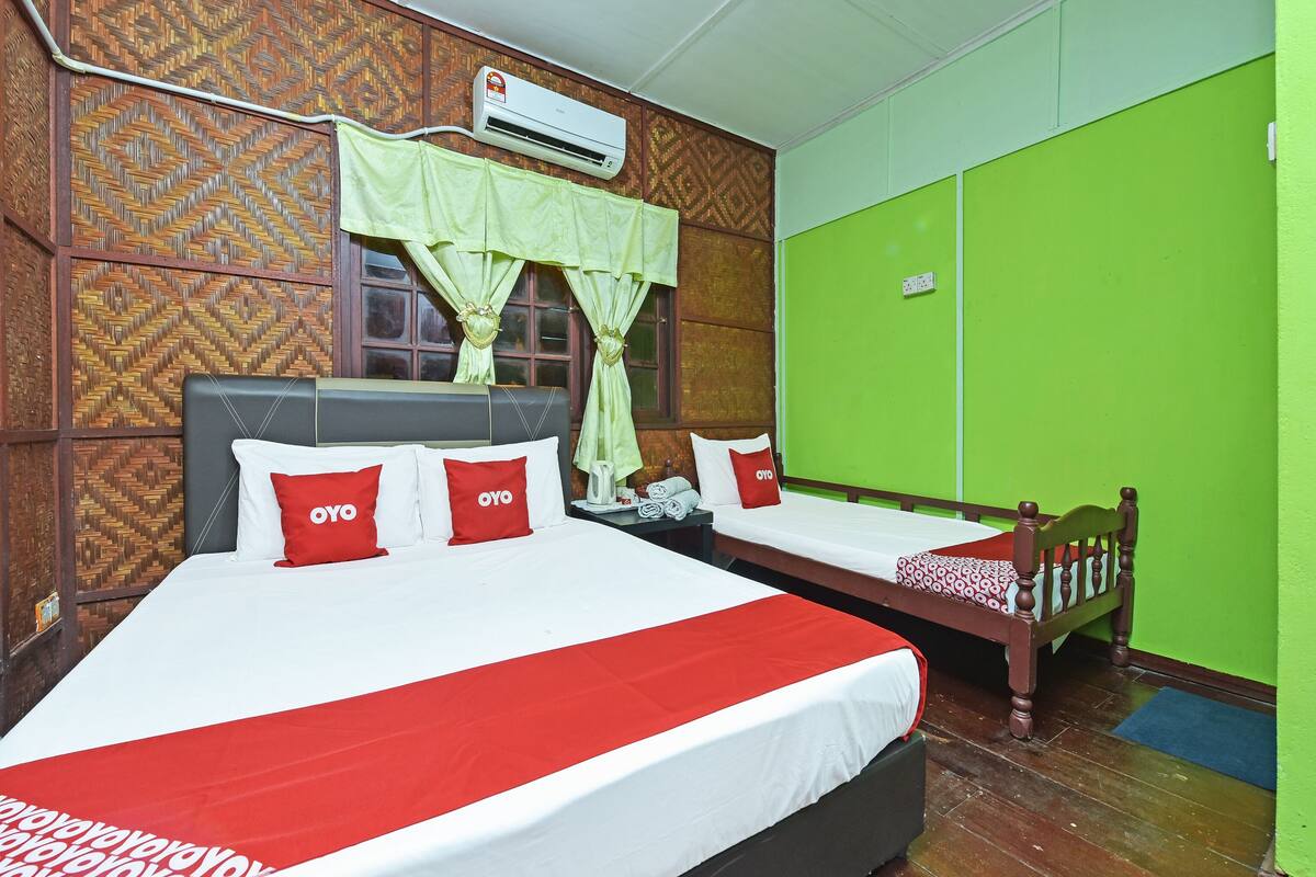 Une chambre d’hôtel avec deux lits, un mur vert, un mur à motifs et un appareil de climatisation.