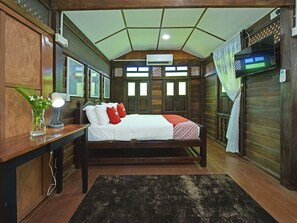 A bedroom with a wooden bed, a bedside table with a lamp, a small plant, and a window with a view of the outside. - Collection O 90622 Sehijau @ Cenang (Langkawi)